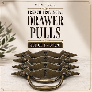 May include: Vintage French Provincial drawer pulls in a set of four. The bronze-colored pulls have a decorative design with a keyhole and a curved handle. The pulls are 3 inches center to center.