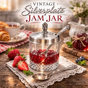 May include: A vintage silver-plated jam jar filled with red jam, a spoon, and a lid. The jar sits on a wooden surface with strawberries, blueberries, and a cup of tea. The text "VINTAGE Silverplate JAM JAR" is at the top.