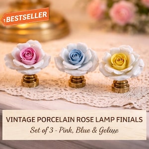 May include: Set of three vintage porcelain rose lamp finials. Each finial features a white rose with a pink, blue, or yellow center, mounted on a gold-colored base. The image includes the text "BESTSELLER" and "VINTAGE PORCELAIN ROSE LAMP FINIALS Set of 3 - Pink, Blue & Gelye."