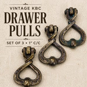 May include: Set of three vintage bronze drawer pulls. Each pull has a unique twisted design with a 1-inch center-to-center measurement. The pulls are a dark bronze color with a distressed finish, perfect for antique furniture.