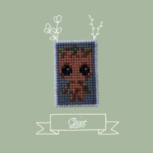 May include: A cross-stitch pattern of Groot from Guardians of the Galaxy. The pattern is on a gray background and features a brown and green character with large eyes. The text "Groot" is written below the pattern.