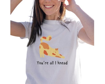 Puede incluir: Camiseta blanca con un gato de dibujos animados estirándose y el texto "You're all I knead".