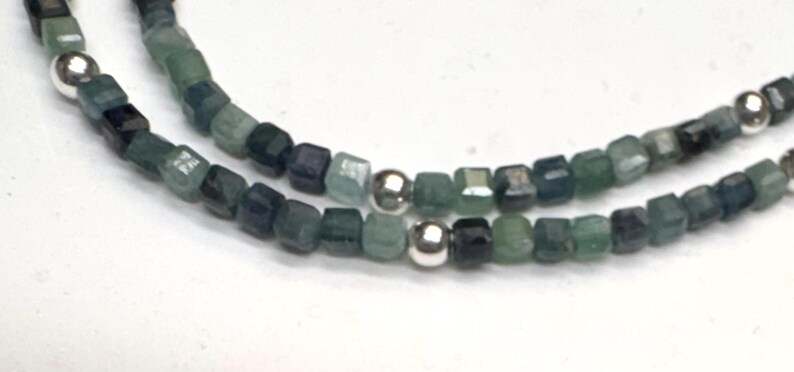 May include: A double strand necklace made with small, square, green and blue gemstone beads and silver spacer beads.