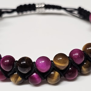 May include: A double-strand bracelet with brown and pink tiger's eye beads, separated by black cord.