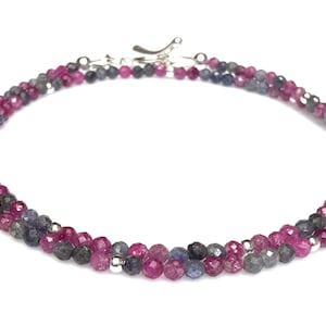 May include: A double-strand necklace featuring faceted beads in shades of pink, gray, and blue. The necklace is secured with a silver clasp. The beads are strung together with silver accents, creating a delicate and elegant piece of jewelry.