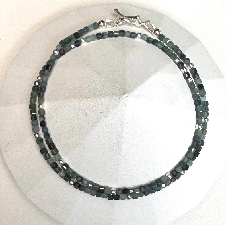 May include: A silver chain necklace with green gemstone beads. The necklace is layered with two strands of beads.