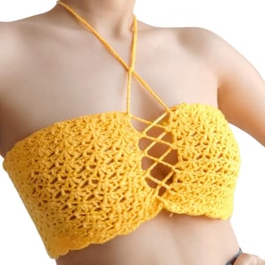 May include: A yellow crochet top with a halter neck and a lace-up design in the center. The top is made of a textured, open-weave fabric. The top is a bright, sunny yellow colour.