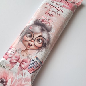 Puede incluir: Un envoltorio de barra de chocolate rosa y blanco con una ilustración de dibujos animados de una niña con gafas y un lazo rosa. El texto en el envoltorio dice "Juffrou volgens my sommetjies is juffrou die beste onnie ooit".