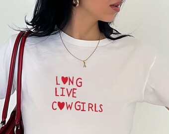 Pode incluir: Camiseta branca com um coração vermelho e o texto "LONG LIVE COWGIRLS" estampado na frente.