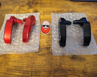 May include: Two sets of door handles, one set is red and the other is black. The handles are made of metal and have a curved shape. They are packaged in bubble wrap.