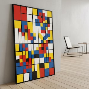 May include: A framed abstract art print featuring a grid of colorful blocks in red, yellow, blue, black, and white. The artwork leans against a wall in a modern interior setting. The frame is black.