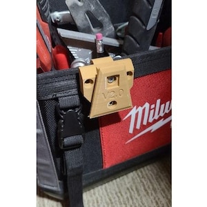 Könnte beinhalten: Ein beigefarbener 3D-gedruckter Werkzeughalter mit dem aufgedruckten Text "V2.0". Der Halter ist an einer schwarzen und roten Werkzeugtasche befestigt.