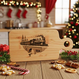 May include: A wooden cutting board with a handle, featuring a detailed engraving of a vintage train on a bridge. The board is light brown with a natural wood grain. Christmas decorations are in the background.