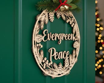 May include: A wooden Christmas wreath with the words "Evergreen Peace" cut out. The wreath is decorated with pinecones, berries, and greenery, and is hanging on a green door. Two small gold bells hang from a red ribbon.