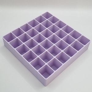May include: A lavender plastic storage organiser with 25 square compartments.