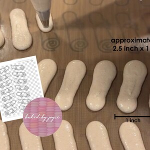 May include: A close-up of a baking sheet with piped meringue cookies in the shape of diplomas. The cookies are approximately 2.5 inches by 1 inch. The text "approximate size 2.5 inch x 1 inch" is visible in the image.