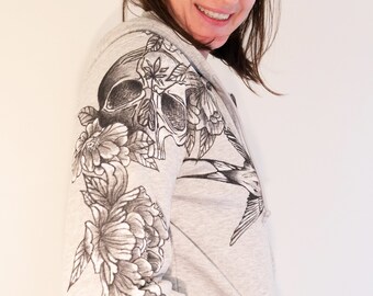 Sweat femme à capuche zippé gris avec poche centrale en coton biologique et polyester recyclé. Fait à la main pour un look rock tatouage.