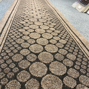 May include: A brown and black doormat with a pattern of circles. The circles are made of a different material than the rest of the mat, giving it a textured look.