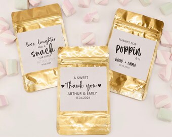 May include: Three gold foil bags with white labels. The labels have text that says "love, laughter and a snack for after Arthur & Emily 11.04.2024", "A sweet thank you Arthur & Emily 11.04.2024", and "Thanks for poppin by! David + Emma 05.16.2024".