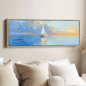 May include: A rectangular framed canvas print showing a sailboat on the sea at sunset. The artwork features a white sailboat with its sail up, reflecting in the blue water. The sky transitions from blue to orange and yellow.