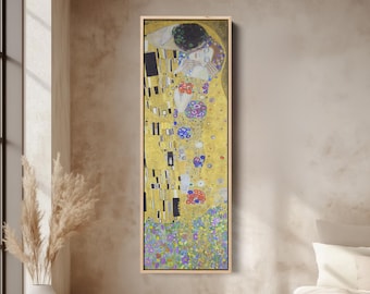Puede incluir: Una impresión vertical enmarcada de "El Beso" de Gustav Klimt muestra a una pareja abrazándose sobre un fondo dorado. La obra de arte presenta patrones intrincados, colores vibrantes y elementos florales, creando un ambiente romántico y artístico.