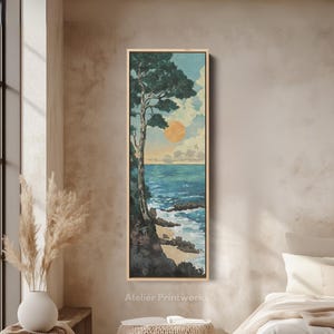 Pode incluir: Uma impressão de arte emoldurada com uma cena costeira. A obra de arte retrata uma árvore em uma costa rochosa, com um oceano azul vibrante e um sol poente. O céu é uma mistura de tons azuis e amarelos. O texto "Atelier Printworks" está na parte inferior.