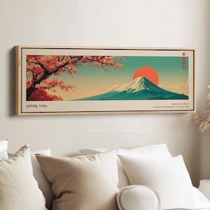 Pode incluir: Uma impressão artística emoldurada com uma paisagem japonesa. A obra de arte retrata o Monte Fuji com um sol poente, flores de cerejeira e o texto "JAPAN 1986". A paleta de cores inclui tons de vermelho, laranja, verde-azulado e bege.