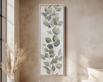 Puede incluir: Impresión vertical en lienzo enmarcado con una ilustración de acuarela de hojas de eucalipto en tonos verdes y grises. La obra de arte tiene un fondo beige claro y un marco de madera natural. El texto "Atelier Printworks" está en la parte inferior.