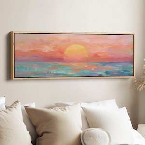 Peut inclure: Peinture encadrée d'un paysage de coucher de soleil sur l'océan. Le ciel est un mélange de roses et d'oranges, avec un grand soleil jaune. L'eau est turquoise et bleue. Le cadre est marron clair.