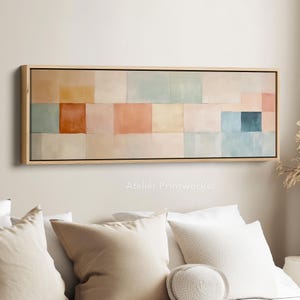 May include: Rectangular abstract artwork in a light wood frame. The artwork displays a grid of colourful squares in shades of peach, orange, blue, and cream. The text "Atelier Printworks." is visible at the bottom.