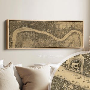 Puede incluir: Un mapa antiguo enmarcado de Londres, con el río Támesis, en tonos sepia. El mapa es rectangular, con un marco de madera clara y un borde negro. El texto "Atelier Printworks" es visible en la parte inferior.