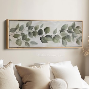Puede incluir: Una obra de arte en lienzo rectangular enmarcada con una pintura de acuarela de hojas de eucalipto en tonos verdes y grises. La obra de arte está sobre un fondo claro y enmarcada en madera natural. El texto "Atelier Printworks." está en la parte inferior.