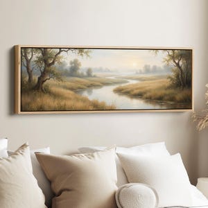 May include: A landscape painting in a rectangular wooden frame. The artwork depicts a serene river winding through a field of tall, golden grass. Trees line the riverbanks, and a soft, hazy light suggests a sunrise or sunset.