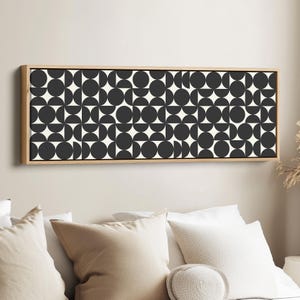 Puede incluir: Una pieza de arte mural rectangular que presenta un patrón geométrico repetitivo de círculos y semicírculos de color gris oscuro sobre un fondo crema, encerrada en un marco de madera clara. El diseño consiste en una cuadrícula de formas circulares.