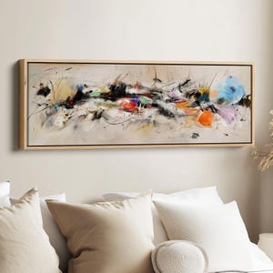 May include: Abstract artwork in a rectangular wooden frame. The painting displays a mix of colours such as black, red, orange, blue, and yellow, with dynamic brushstrokes and splatters on a neutral backdrop.
