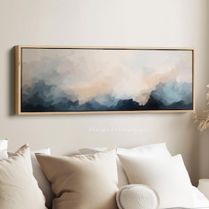 Könnte beinhalten: Abstrakte Landschaftsmalerei in einem rechteckigen Holzrahmen. Das Kunstwerk zeigt eine Mischung aus Blau-, Beige- und Weißtönen, die einen ruhigen, wolkenartigen Effekt erzeugt. Das Gemälde ist an einer Wand über einem Bett mit weißen Kissen angebracht.