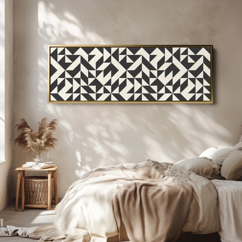 Puede incluir: Una pieza de arte mural rectangular que presenta un patr&oacute;n geom&eacute;trico repetitivo de tri&aacute;ngulos y cuadrados en negro y blanco roto. La obra est&aacute; encerrada en un marco fino de metal dorado, mostrando un dise&ntilde;o sim&eacute;trico de alto contraste.