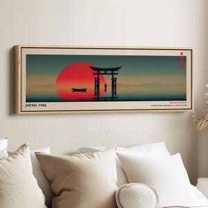 Könnte beinhalten: Gerahmter Kunstdruck mit einer japanischen Landschaft, die eine große rote Sonne, ein traditionelles Torii-Tor und ein Boot auf dem Wasser zeigt. Der Druck enthält den Text "JAPAN 1986" und japanische Schriftzeichen. Das Kunstwerk ist in einem Holzrahmen.