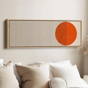 Könnte beinhalten: Rechteckiger Kunstdruck in einem Holzrahmen. Das Kunstwerk zeigt einen cremefarbenen Hintergrund mit vertikalen schwarzen Linien auf der linken Seite und einem orangefarbenen Kreis auf der rechten Seite. Der Druck ist über einem Bett montiert.