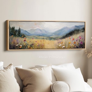Op de afbeelding: Een landschapsschilderij in een rechthoekige houten lijst. Het kunstwerk toont een veld met wilde bloemen op de voorgrond, met glooiende heuvels en bergen op de achtergrond. Het kleurenpalet omvat blauw, groen, geel en paars. De tekst "Atelier Printworks." staat onderaan.