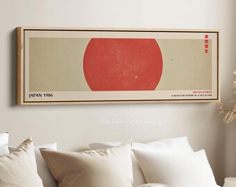 Puede incluir: Una impresión artística enmarcada con un círculo rojo sobre un fondo beige, con el texto "JAPAN 1986" en negro. También hay texto japonés. La obra de arte se muestra en un marco de madera natural, adecuada para la decoración de paredes.