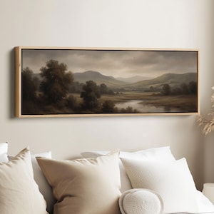 Peut inclure: Peinture de paysage dans un cadre en bois rectangulaire. L'œuvre représente une scène de vallée sereine avec une rivière, des arbres et des collines sous un ciel nuageux. La palette de couleurs est sourde, avec des nuances de brun, de vert et de gris.