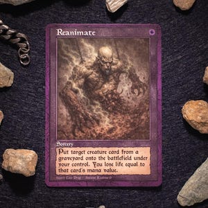 Può includere: Una carta viola "Reanimate" della serie "Ancient Realms". La carta presenta un'illustrazione dettagliata di una figura mostruosa. Il testo descrive la funzione della carta. La carta è circondata da rocce e una catena d'argento.