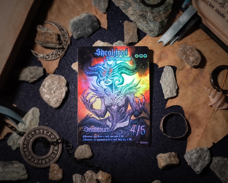 Op de afbeelding: Een rechthoekige ruilkaart met Sheoldred the Apocalypse met een holografische afwerking. Het kunstwerk toont een gehoornde figuur met meerdere ogen, een paarse huid en uitgestrekte handen. De kaart bevat de tekst Deathtouch, 4/5 en manasymbolen.
