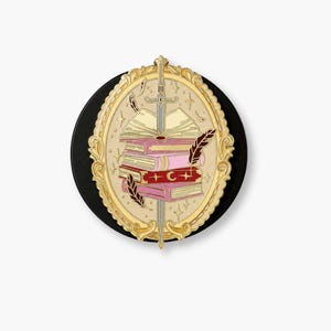 Puede incluir: Un pin esmaltado circular con un marco ovalado dorado y ornamentado que rodea una pila de libros atravesados por una espada plateada. Los libros son de tonos rosa y rojo, con un símbolo de media luna en el lomo rojo y plumas flotantes.