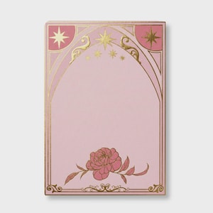 Può includere: Un blocco note rosa con bordo e dettagli dorati. Il design include stelle, un arco e una rosa in basso. Il blocco note ha una forma rettangolare e uno spazio vuoto per la scrittura.