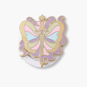 Könnte beinhalten: Eine goldfarbene Emaille-Anstecknadel mit einem zentralen Schwertdesign, das auf Schmetterlingsflügeln liegt. Die Flügel sind in Pastellrosa, Hellblau und Hellgrün unterteilt und von wirbelnden violetten Akzenten sowie einem Goldrand umrahmt.