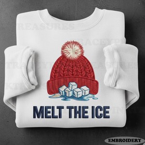 以下が含まれることがあります： 白いスウェットシャツ。赤いニット帽と白いポンポン、溶けた氷のグラフィック。ネイビーブルーの「Melt the Ice」の文字が下にプリントされています。スウェットシャツは長袖です。