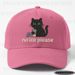 Puede incluir: Gorra de béisbol rosa con un diseño de gato negro sosteniendo una taza de café y cubitos de hielo. El texto "no ice please" está bordado debajo. La gorra tiene una visera curva y un botón en la parte superior.