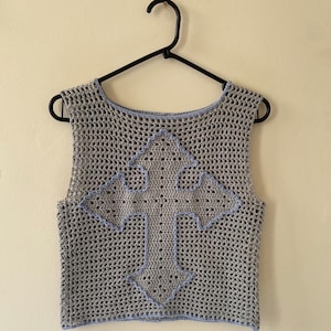 Könnte beinhalten: Ein graues Häkeltop mit einem blauen Kreuzdesign. Das Top ist ärmellos und hat einen runden Ausschnitt.